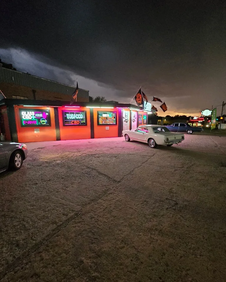 Pit's Smoke Shop completed exterior painting at dusk - vibrant orange building with neon lights and classic car in Stillwater OK